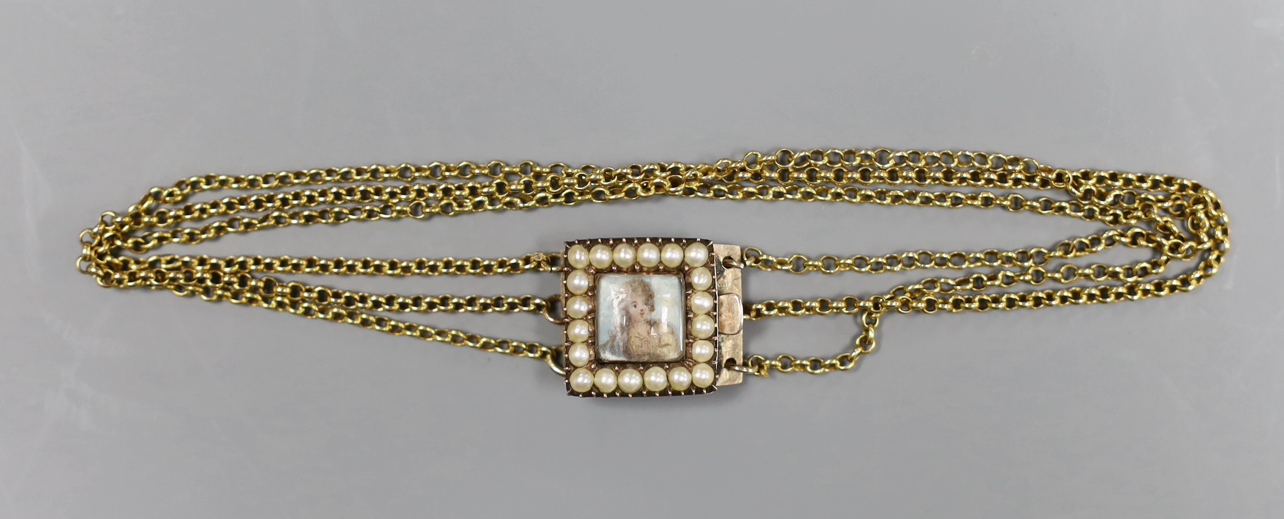 An early 19th century seed pearl set gold bracelet clasp, inset with a miniature of a lady, 1.5cm, on later? triple chain bracelet, gross 7.6 grams